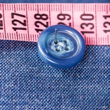 Attaching of button to blue silk fabric by needle Stock Photos
