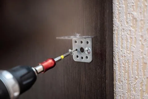 Attaching metal bracket to chipboard using cordless screwdriver for constru.. Stock Photos