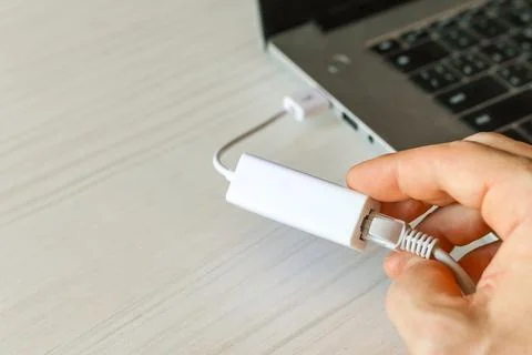 Attaching network cable to adapter beside connected laptop Stock Photos