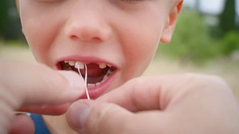 An attempt to pull out the boy's front milk tooth with a thread. Stock Footage 246979722