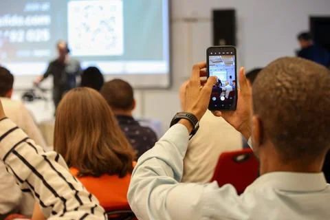 Attendee using phone to record a dynamic presentation at a seminar. Ideal for Stock Photos
