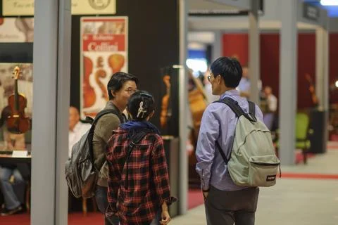 Attendees Engage in Discussions Amidst Exquisite Stringed Instruments on Di.. Stock Photos