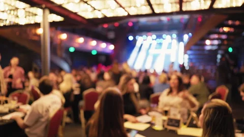 Attendees at fundraising dinner focus on stage while servers attend to guests Stock Footage 332245517