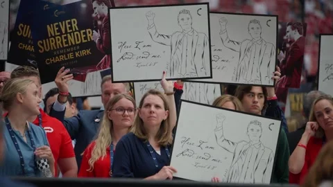 Attendees hold signs reading Never Surrender at the Charlie Kirk memorial Stock Footage 345298096