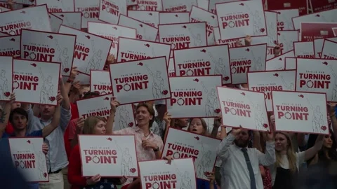 Attendees hold up Turning Point Action signs in the stadium Stock Footage 345298065