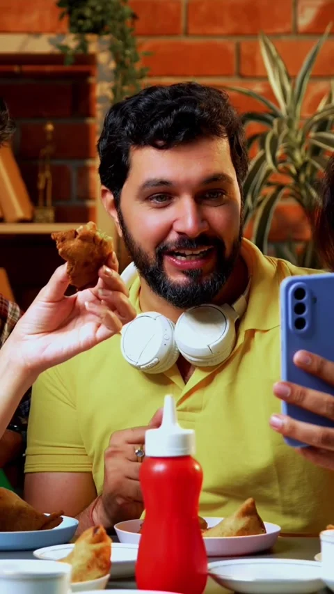 Attending video call in cafe while enjoying snack, students connect virtually Stock-Footage 342385133