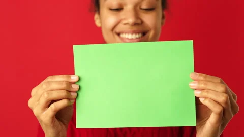 Attention. Close up of smiling mixed race girl showing empty blank paper sign Stock Footage 146129622