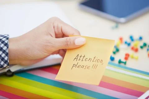 Attention please text on adhesive note Human hand holding adhesive note wi... Stock Photos