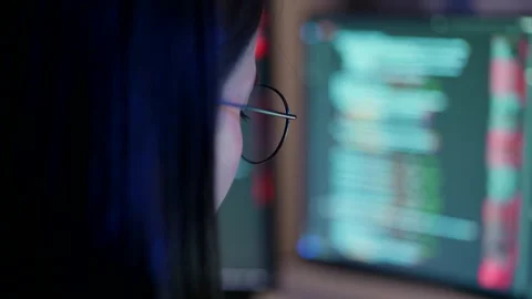 An attentive female developer with glasses analyzing source code on a compute Stock Footage 310589115