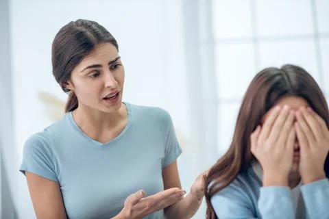 Attentive knowledgeable mother talking to turned away daughter Stock Photos