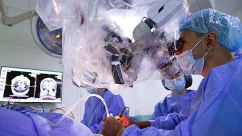 Attentive neurosurgeon performs brain surgery using modern technological microsc Stock Footage 262007228