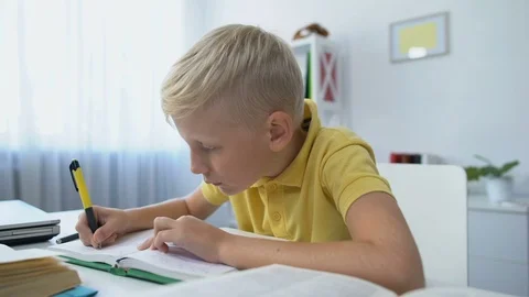 Attentive schoolboy doing homework, writing task in notebook, distant education 動画素材 118989809