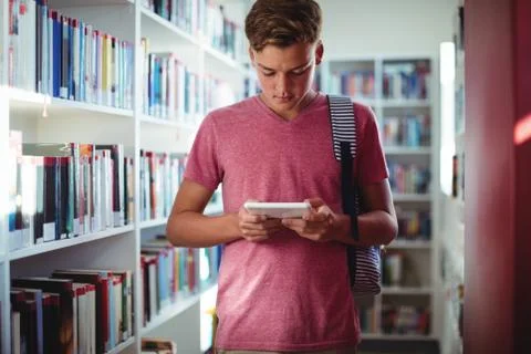 Attentive schoolboy using digital tablet in library Stock Photos