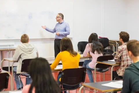 Attentive students with teacher in the classroom Stock Photos