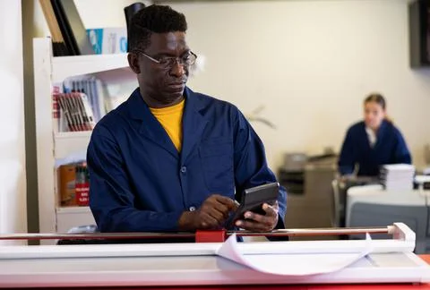 Attentive technical worker of printing house counts the cost of payment for work Stock Photos