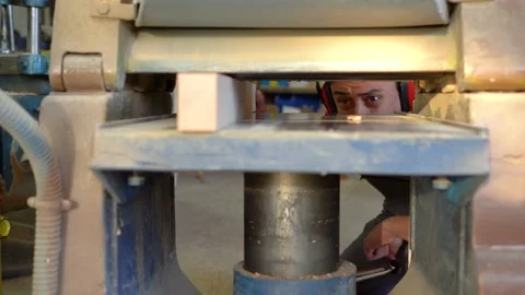 Attentive woodworker using thicknesser machine to trim wooden board Stock Footage 172283473