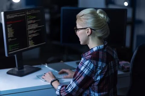 Attentive young IT girl decoding in the dark lighted room Stock Photos