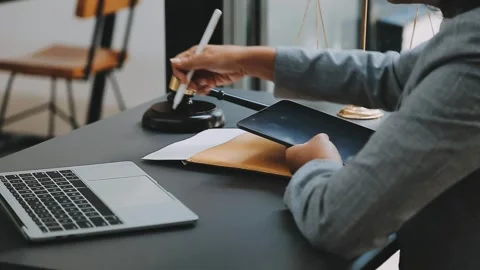 Attorney analyzes data on tablet near gavel and scales of justice Stock Footage 325419131
