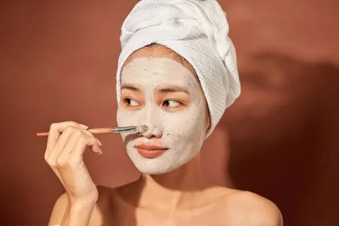 Attracitve young Asian woman applying clay mask on her facee. Spa and wellnes Stock Photos