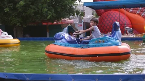 Attractions on the water. Children in the pool on electric boats Stock Footage
