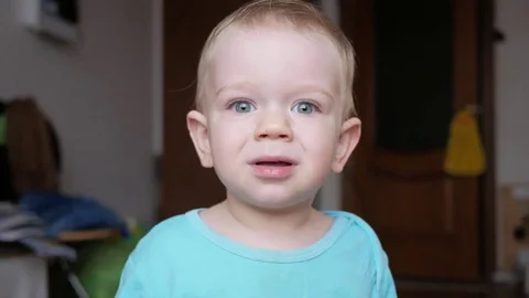 Attractive 2 year old boy looks at the camera and smiles and changes facial Stock Footage 73841255
