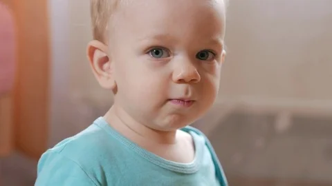 Attractive 2 year old boy looks at the camera and smiles and changes facial Stock Footage 73841593