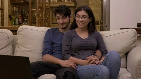 Attractive affectionate young couple watching movie on laptop at home in the  Video stock 83046489