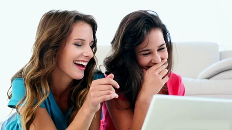 Attractive amused women using notebook lying on floor Stock Footage 32880107