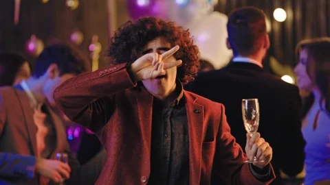 Attractive and funny guy with a curly hair holding a glass of champagne in front Stock-Footage 122077083