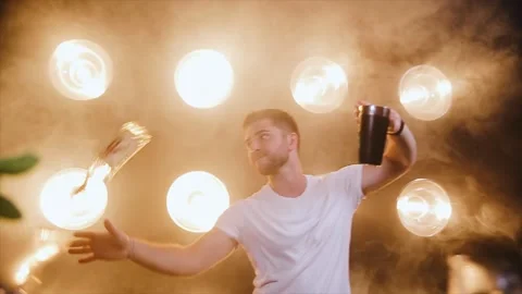Attractive bartender professionally juggling cups and doing a show in modern bar Stock Footage 136197590