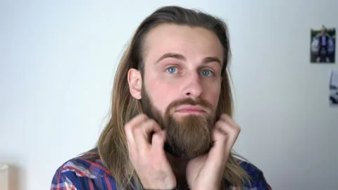 Attractive beard  man is looking into the mirror with long hair Stock Footage 147898284