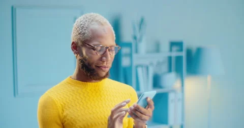 Attractive bearded black man using a mobile phone thinking and typing message on Video stock 163146030