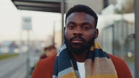 Attractive bearded black man in winter coat and scarf standing at public Stock Footage 121476090