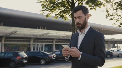 Attractive Bearded Businessman using Smartphone while the Walk near the Office Stock Footage 111075992