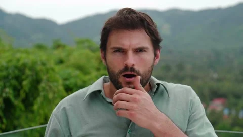 Attractive bearded dark-haired young Hispanic man looks at the camera through Stock Footage 218565916