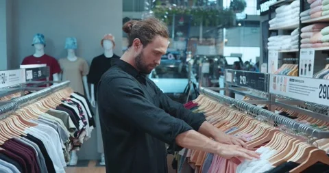 Attractive bearded macho man in dark casual shirt, shopping for t shirts in Stock Footage 271071548