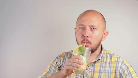 Attractive bearded man drinking lemonade or mojito cocktail from a glass Stock Footage 158861486