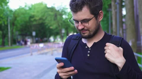 Attractive bearded man in glasses using phone on the street Stock Footage 134697254
