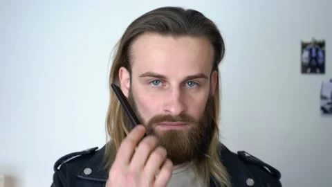 Attractive bearded man in leather jacket is Combing His Beard Stock Footage 147898558