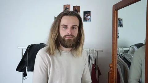 Attractive bearded man is looking into the mirror  he straightening his hair Stock Footage 147899438