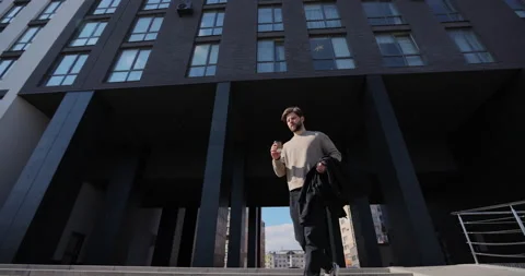 Attractive bearded man running down stairs and drinking take away coffee while Stock Footage 237249426