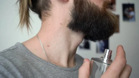 Attractive  bearded man is spraying perfume Stock Footage 147900784