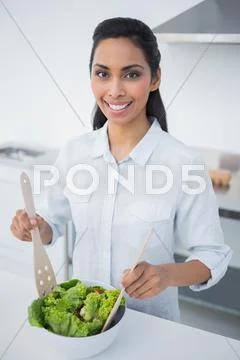 Attractive black haired woman preparing salad in kitchen Stock Photos