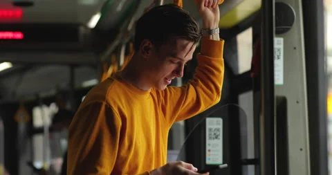 Attractive blond guy stands in public transport and uses a smartphone. Stock Footage 133419947