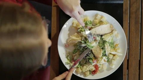 Attractive blonde eats at a cafe a salad with chicken in a cafe. Video stock 103690850