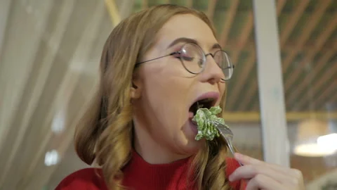 Attractive blonde eats at a cafe a salad with chicken in a cafe. Video stock 103700270