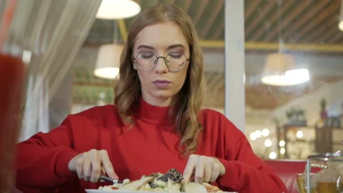 Attractive blonde eats at a cafe a salad with chicken in a cafe. Video stock 105239348