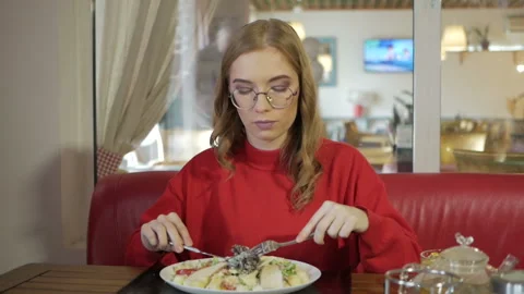 Attractive blonde eats at a cafe a salad with chicken in a cafe. Video stock 105239771