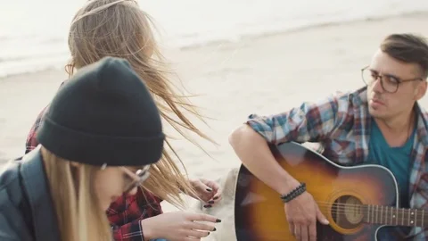 Attractive blonde laughs and claps her hands, a guy with glasses plays guitar Video stock 75689051