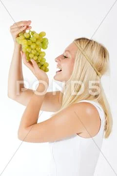 Attractive blonde woman eating grapes Stock Photos